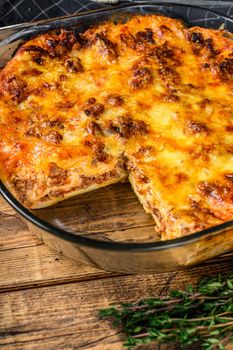 Lasagna with bolognese sauce and mince beef in a baking dish. Wooden background. Top view.