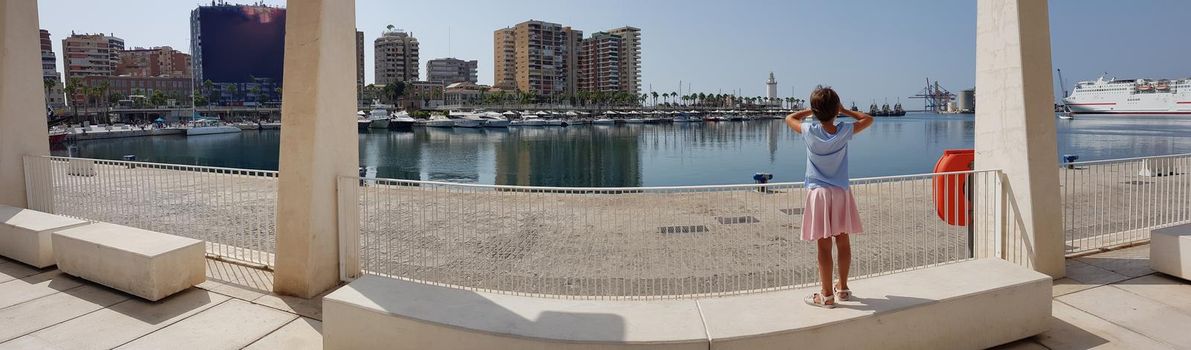 Panoramic view of little girl looking at the Port of Malaga in Andalusia, Spain.