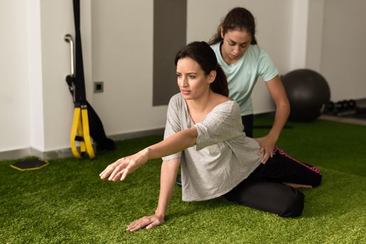 Physical therapist assisting young caucasian woman with exercise during rehabilitation in the gym at hospital. Female physiotherapist training a patient in physiotherapy center.