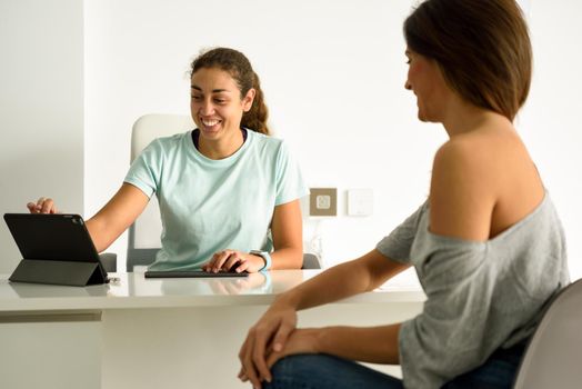 Female physiotherapist explaining diagnosis to her patient. Brunette woman having consultation with girl in medical office.