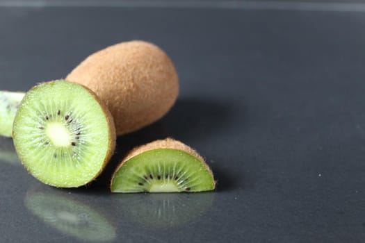 A few three pieces of kiwi lie in a pile on a black background with a copy .
