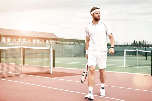 Tennis player in white sportswear with the racket and the ball in his hands is going to play tennis. Horizontal shot