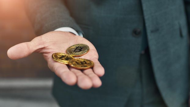 Virtual money. Cropped photo of a man holding many bitcoins in hand. Cryptocurrency