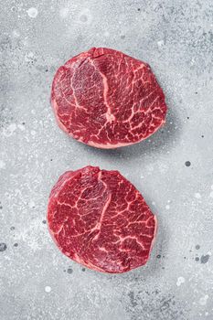 Raw fillet Mignon beef steaks on a butcher board. Gray background. Top view.