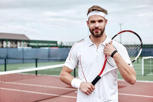 Portrait of tennis player man. Front view. Looking at camera. on the court