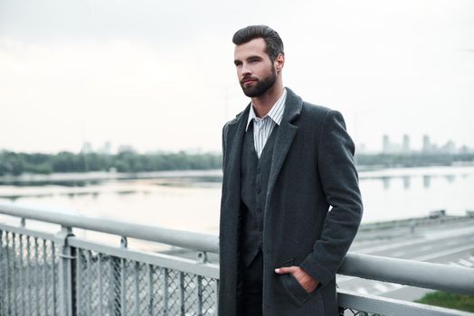 Confidence. Businessman standing on the bridge looking aside pensive