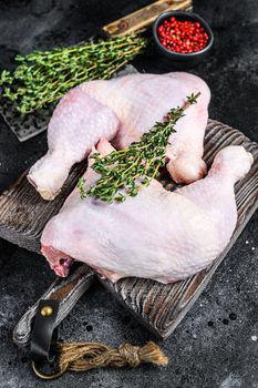Fresh raw chicken legs on a cutting board. Black background. Top view.