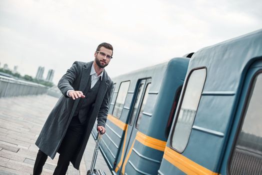 Late for train. Young businessman running near railway with luggage