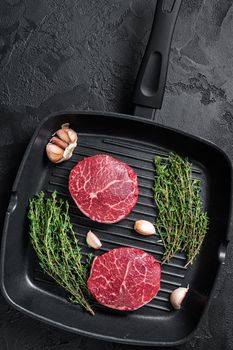 Tenderloin Raw Fillet Mignon beef steaks on a pan. Black background. Top view.