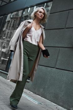 Fashion. Young stylish woman walking on the city street looking forward thoughtful full body shot