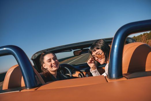 Two happy friends in the cabriolet driving everywhere and looking for freedom and fun