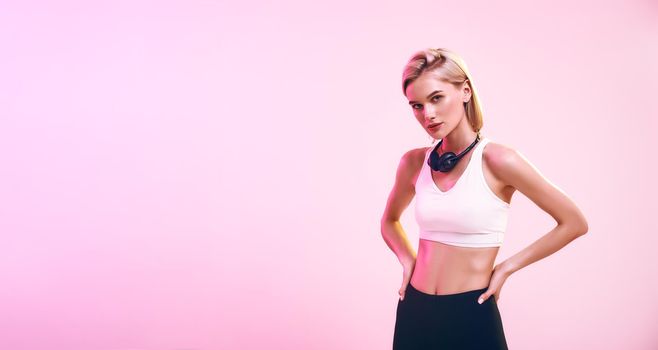 Music for workout. Beautiful and sporty woman in headphones looking at camera while standing against pink background. Sport. Music concept. Web banner