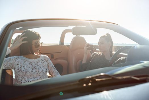 Two happy friends in the cabriolet driving everywhere and looking for freedom and fun