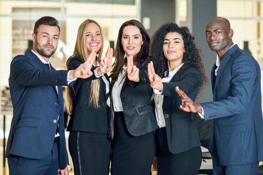 Group of businesspeople with thumbs up gesture in modern office. Multi-ethnic people working together. Teamwork concept.
