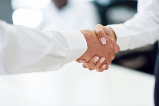 Caucasian businessman shaking hands with businesswoman wearing suit in a office. Close-up shot