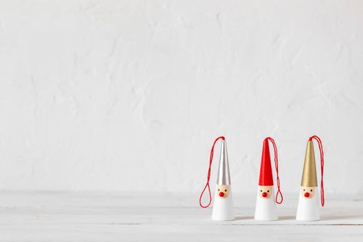 three Santa Clauses figurines on a white wooden background, side view, copy space