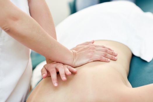 Young woman receiving a back massage by professional therapist. Female patient is receiving treatment in a spa center.