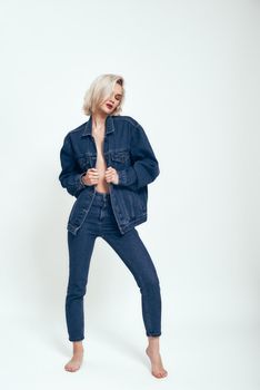 Confident and sexy. Full length of attractive young woman in jeans wear looking aside while standing against grey background in studio. Denim. Fashion concept. Beauty