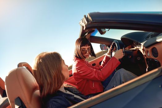 Two happy friends in the cabriolet driving everywhere and looking for freedom and fun