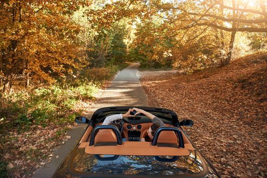 Female friends driving cabriolet with the hands up and having fun on the vacation