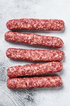 Fresh raw beef meat kebabs sausages. White background. Top view.