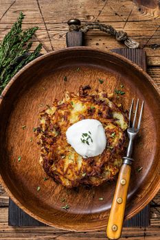Roasted Potato pancakes or Fritters with herbs in a wooden plate. wooden background. Top view.
