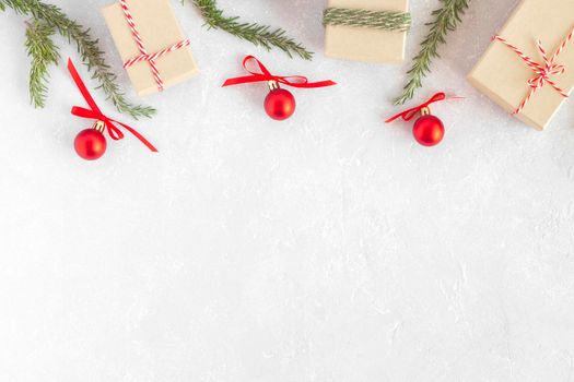 christmas gift boxes, new year tree branches and red decorative balls on light grey background, top view, copy space