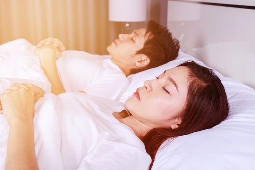 young couple sleeping on a comfortable bed in bedroom at home