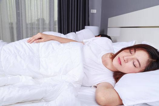 young woman sleeping with her husband in a comfortable bed at home