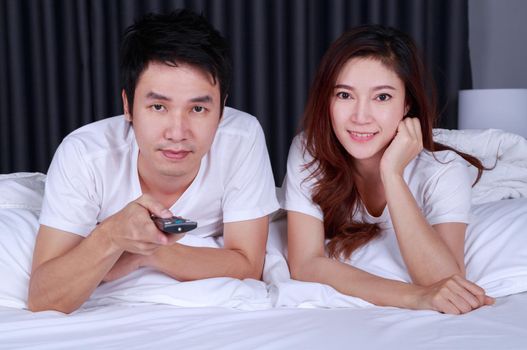 young couple watching movie on bed in the bedroom