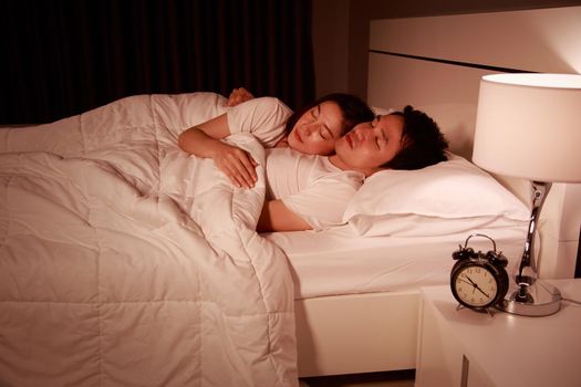 happy young attractive couple hugging and sleeping on bed at night