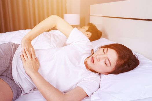 young woman stomach pain on bed with her hunsband