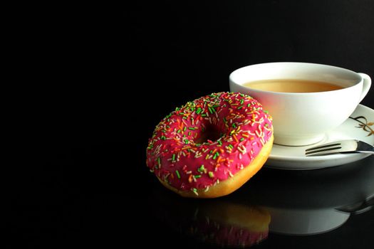 Doughnut with pink icing berliner lies next to a cup of coffee tea delicious breakfast snack day without diet on black background copyspace.