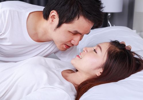 young lovely couple lying in a bed and looking to each other (eyes to eyes)