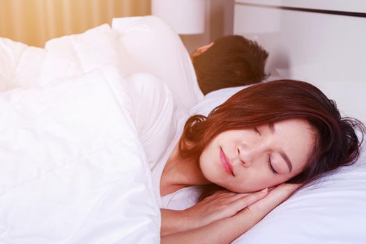 young woman sleeping with her husband in a comfortable bed at home