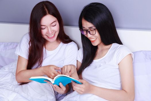 two woman reading a book on bed in the bedroom