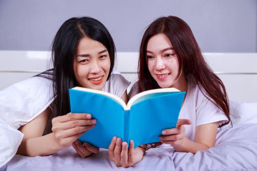 two woman reading a book on bed in the bedroom