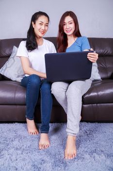 two young woman using a laptop computer on sofa in living room at home