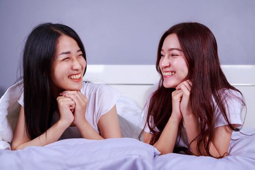 two happy woman lying on bed in the bedroom