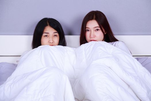 two best friend woman on bed watching a tv with shocked expression on face