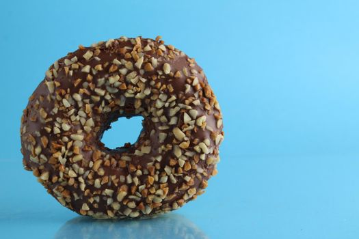 Berliner donut pink chocolate lies stands on a blue bright background with a place to text a copy of the still life breakfast meal.