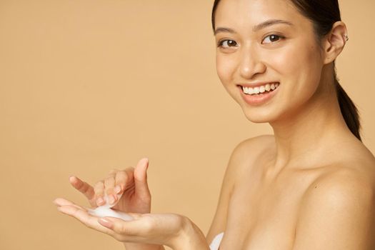 Beauty portrait of lovely young woman smiling at camera ready to apply gentle foam facial cleanser. Beauty products and skin care concept