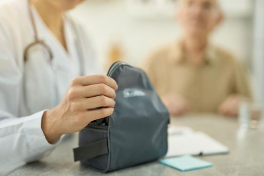 Cropped photo of healthcare worker in white uniform opening a bag with medical equipment