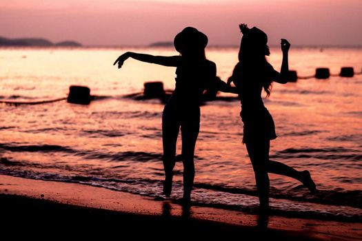 Silhouette of two young woman having fun on the sea beach