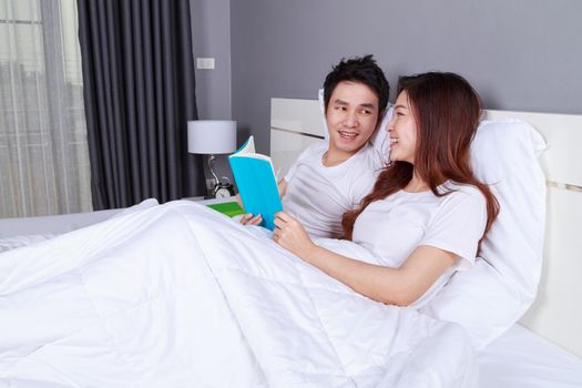 young couple reading a book on bed in the bedroom