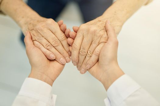 Fragment photo of hands of a healthcare worker touching hands of an elderly patient