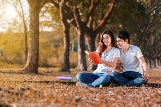 man and woman sitting and reading a book in the park