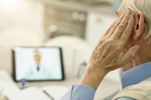 Fragment photo of elderly man touching his head while having a video online consultation with medical specialsit