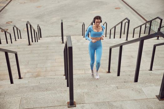 Beautiful fit caucasian woman is doing exercises outdoors at the city