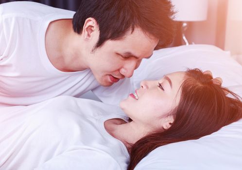 young lovely couple lying in a bed and looking to each other (eyes to eyes)